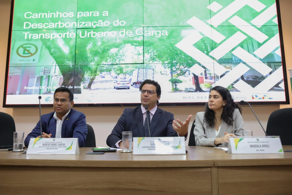 Mesa do evento com dois homens e uma mulher.
